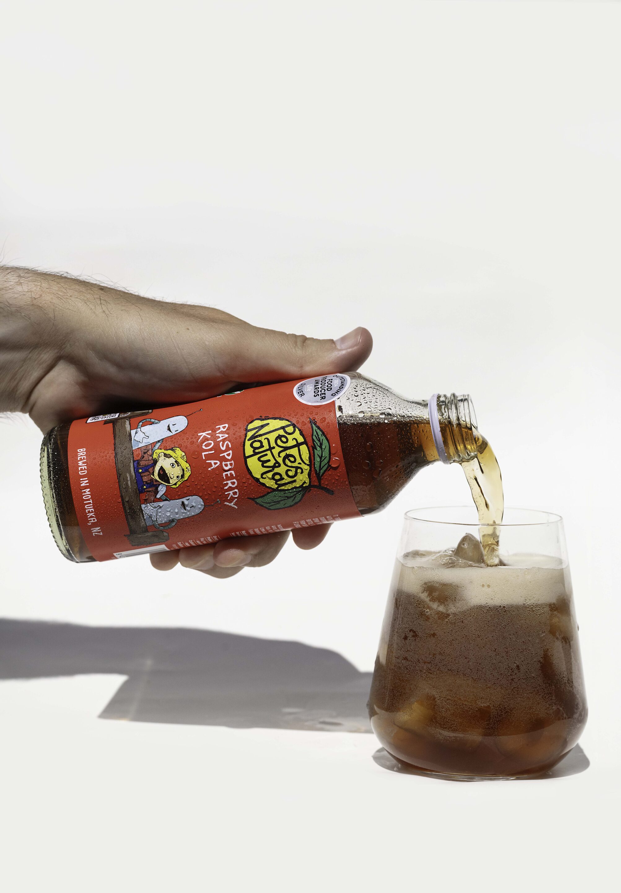 Raspberry Kola poured into a glass of ice